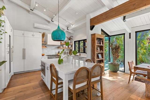 kitchen with white cabinetry, hanging light fixtures, a kitchen island, and a healthy amount of sunlight