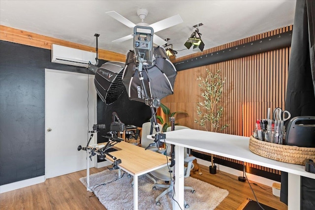 exercise area with a wall unit AC, ceiling fan, wood-type flooring, and wood walls