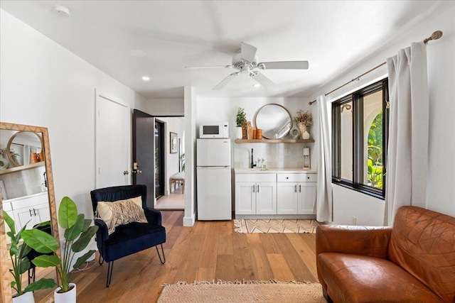 living area with ceiling fan, sink, and light hardwood / wood-style flooring