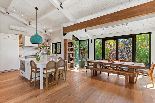 dining room with beam ceiling, light hardwood / wood-style floors, an AC wall unit, and sink