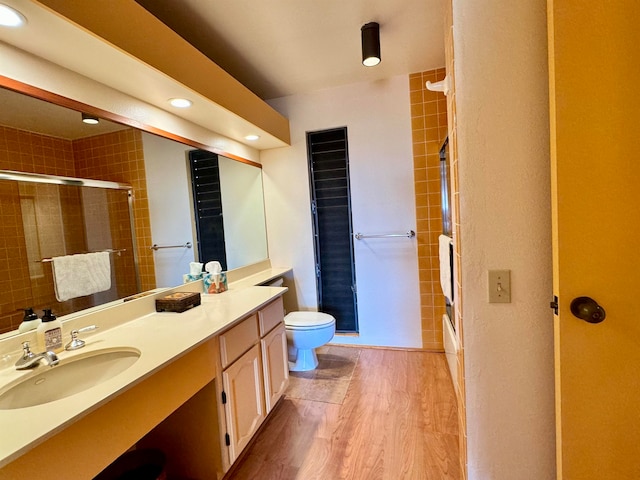 full bathroom featuring wood-type flooring, vanity with extensive cabinet space, toilet, and enclosed tub / shower combo