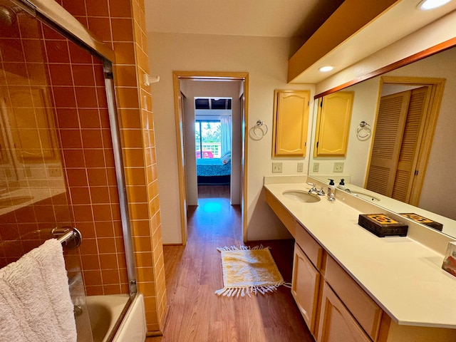 bathroom featuring hardwood / wood-style floors, combined bath / shower with glass door, and vanity