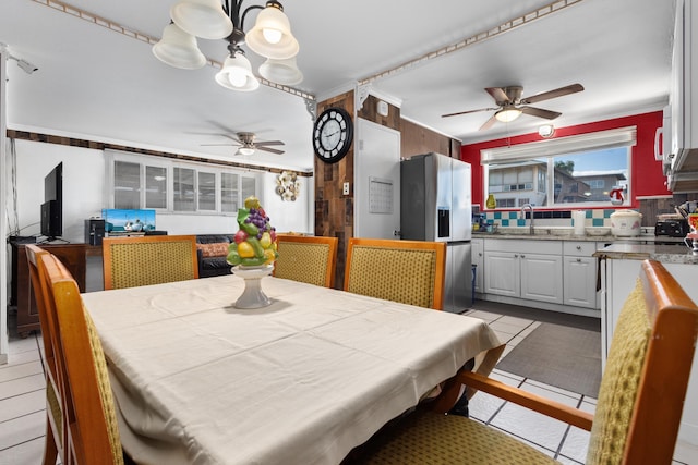 dining space with light tile patterned floors, ceiling fan, crown molding, and sink