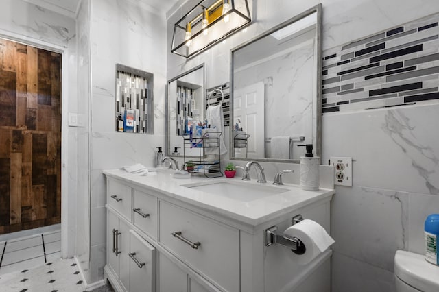 bathroom with vanity, tile walls, and toilet