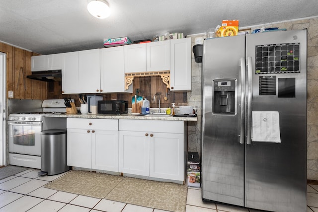 kitchen with stainless steel fridge, white range with gas cooktop, sink, white cabinetry, and light tile patterned flooring