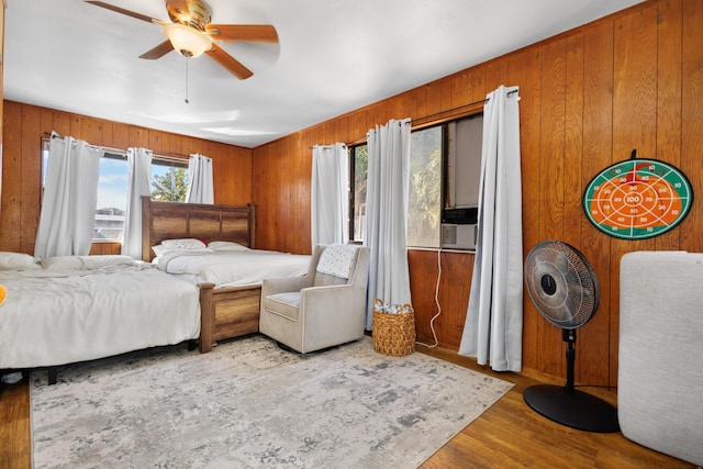 bedroom featuring ceiling fan, wooden walls, and light hardwood / wood-style floors