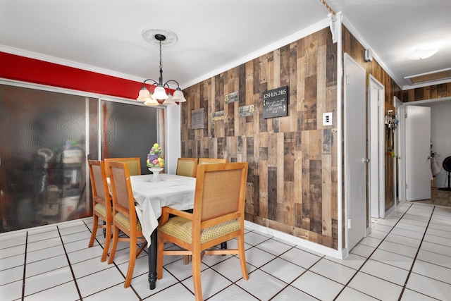 dining area with light tile patterned floors, ornamental molding, wooden walls, and a chandelier