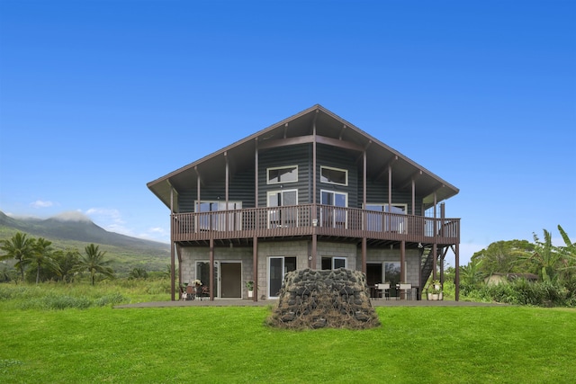 rear view of house featuring a deck with mountain view and a yard