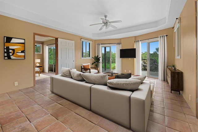 tiled living room featuring ceiling fan and a tray ceiling