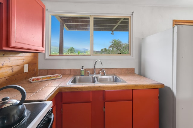 kitchen with tile countertops, sink, and range