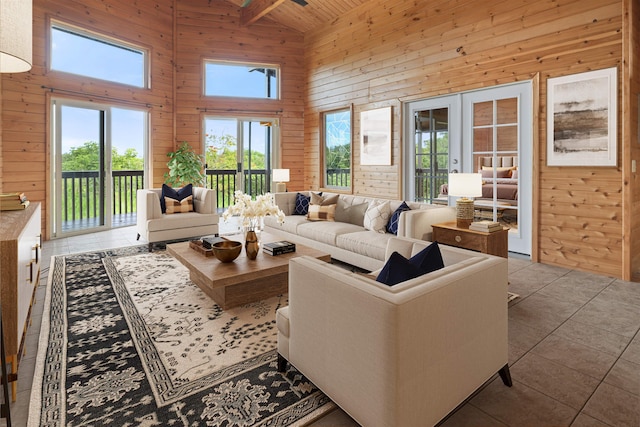 living room featuring wood ceiling, beam ceiling, high vaulted ceiling, wooden walls, and light tile patterned floors