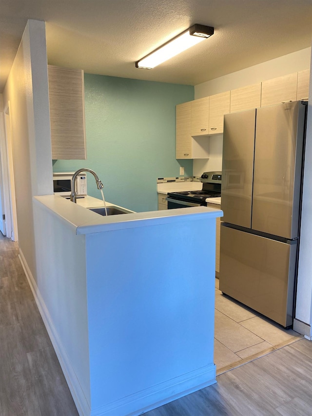 480 Kenolio Rd Unit 23-202, Kihei, HI 96753 - kitchen featuring stainless steel appliances, light wood-style flooring, a peninsula, light countertops, and a textured ceiling