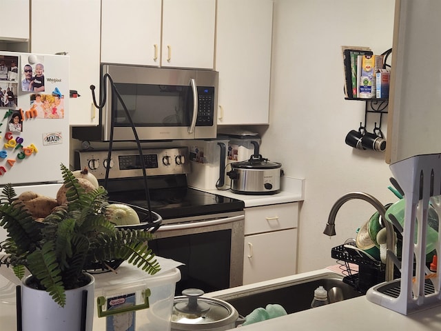 kitchen with stainless steel appliances, light countertops, and white cabinets