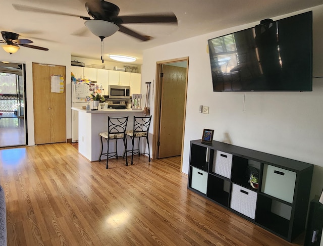 kitchen featuring light countertops, appliances with stainless steel finishes, light wood-style floors, white cabinets, and a kitchen breakfast bar