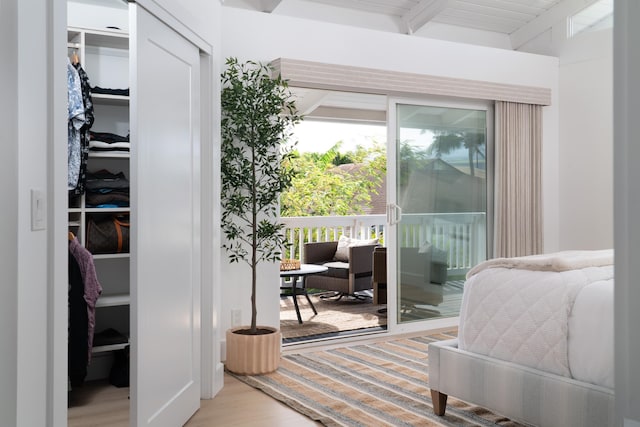 interior space with beamed ceiling, access to outside, wood finished floors, and a closet