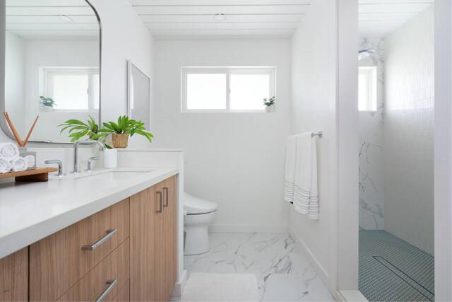 full bath with vanity, baseboards, tiled shower, toilet, and marble finish floor