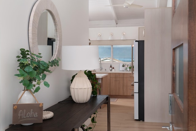 interior space with a sink, beam ceiling, and light wood-style floors