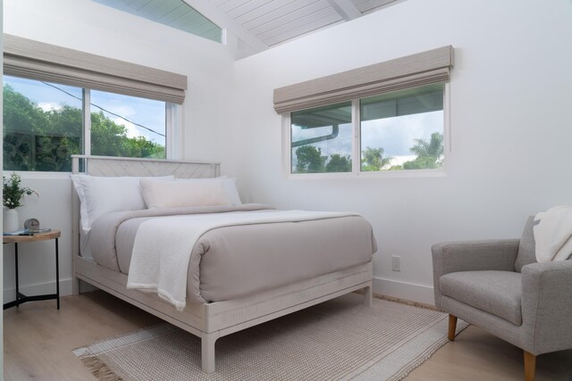 bedroom with lofted ceiling, light wood-style flooring, and baseboards