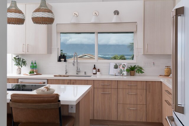 kitchen featuring decorative backsplash, light countertops, modern cabinets, and a sink