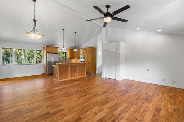 kitchen featuring hardwood / wood-style floors, lofted ceiling with beams, stainless steel appliances, hanging light fixtures, and tasteful backsplash