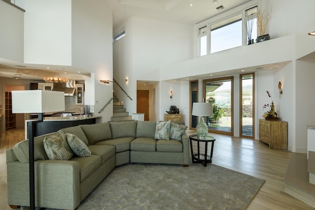 living room featuring a towering ceiling, hardwood / wood-style flooring, and a chandelier