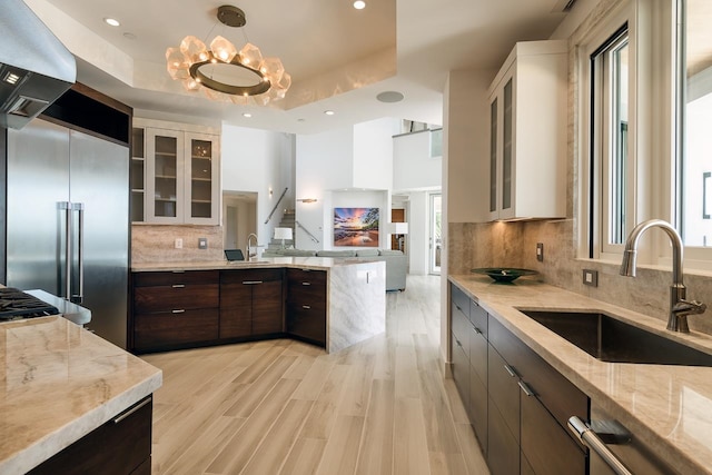 kitchen with sink, tasteful backsplash, a raised ceiling, and white cabinetry