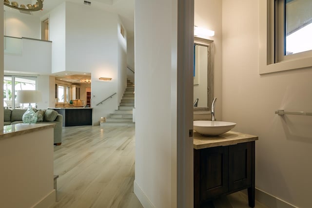 bathroom with a towering ceiling, wood-type flooring, and vanity