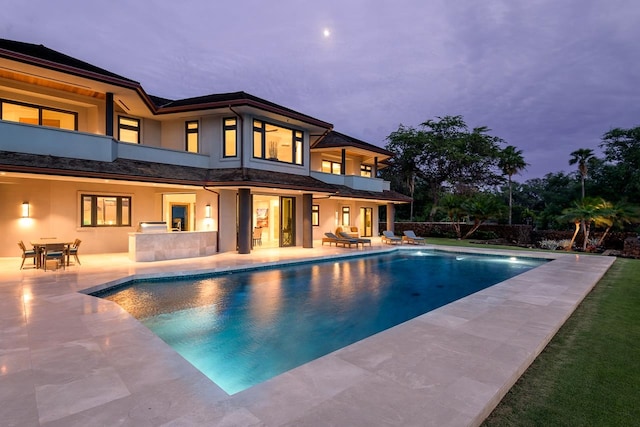 pool at dusk featuring a patio