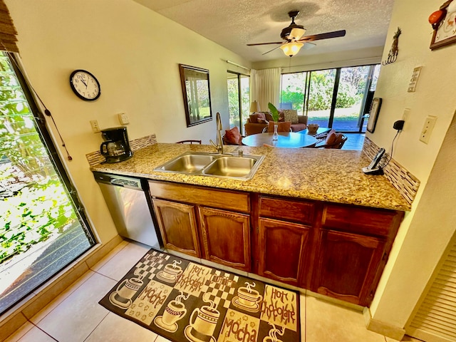 kitchen with ceiling fan, sink, light tile floors, stainless steel dishwasher, and a textured ceiling