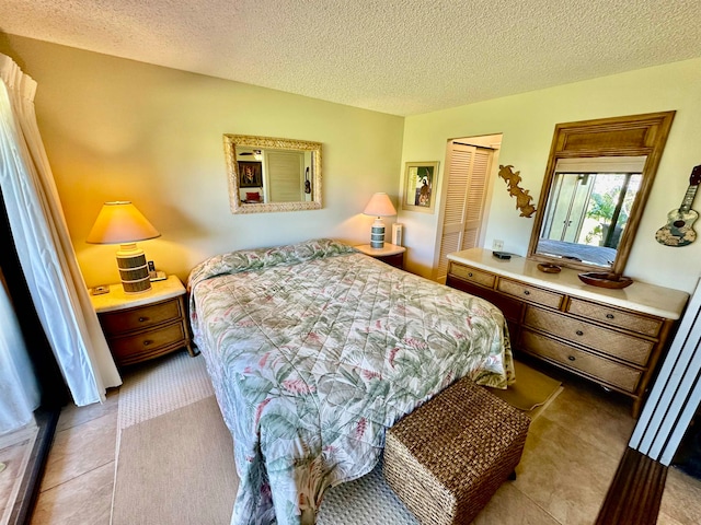 tiled bedroom with a closet and a textured ceiling