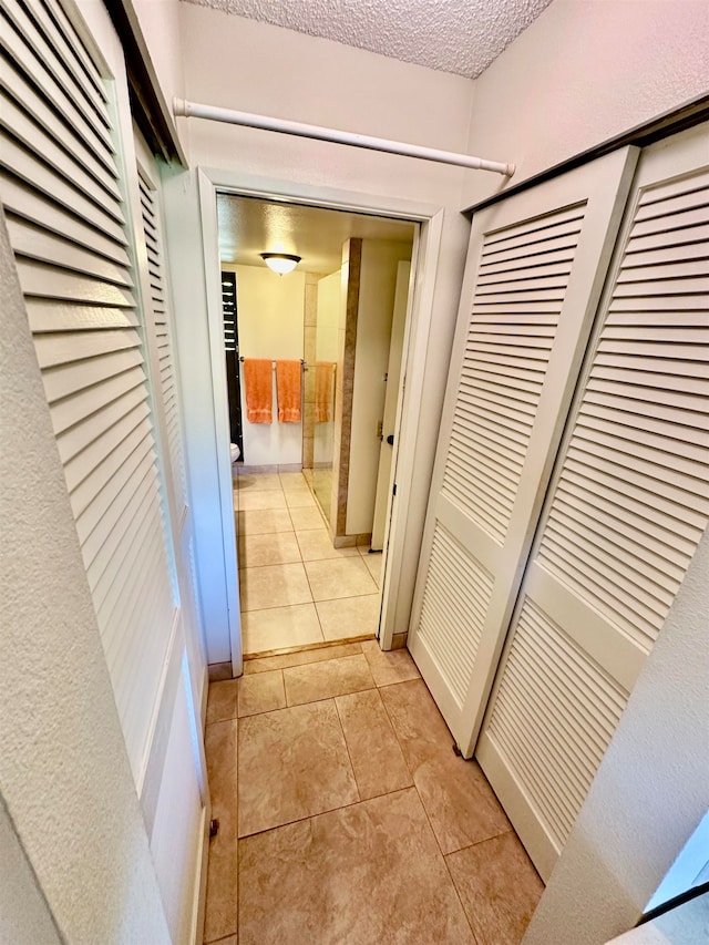 hallway with light tile flooring and a textured ceiling