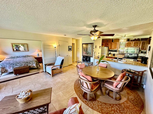 tiled dining room featuring a textured ceiling, ceiling fan, and sink