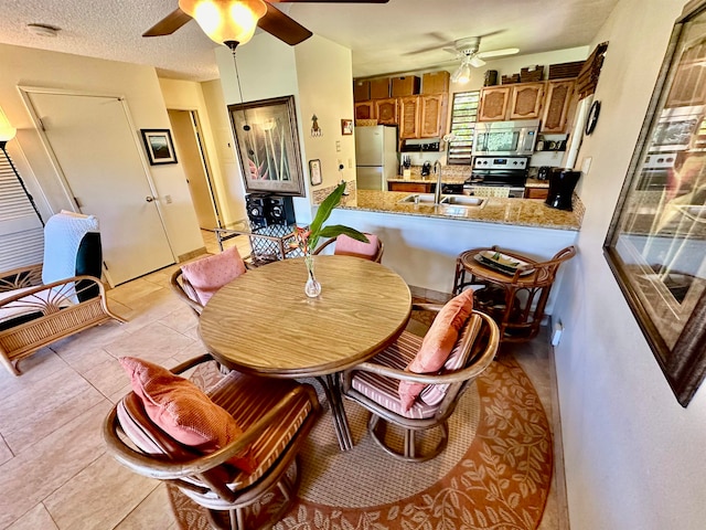 dining space featuring light tile floors, ceiling fan, a textured ceiling, and sink