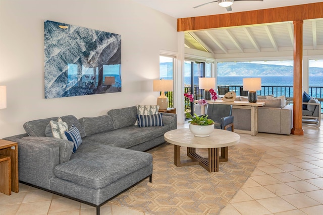 living room featuring vaulted ceiling with beams, ceiling fan, a water view, and light tile patterned floors