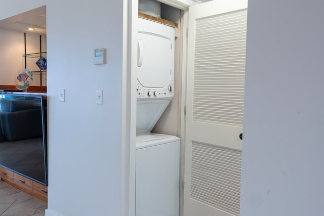 laundry room with tile patterned floors and stacked washing maching and dryer