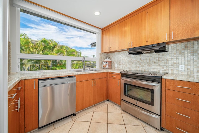 kitchen with a healthy amount of sunlight, sink, light tile patterned floors, and stainless steel appliances