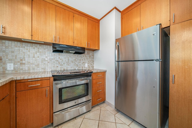 kitchen featuring decorative backsplash, appliances with stainless steel finishes, and light tile patterned flooring