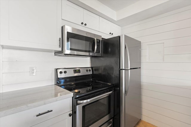 kitchen with appliances with stainless steel finishes, white cabinetry, and light stone counters