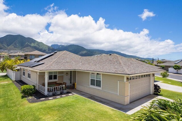 view of front of home with a garage, a mountain view, a porch, a front yard, and solar panels