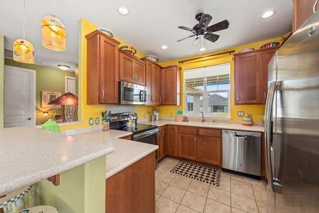 kitchen with kitchen peninsula, hanging light fixtures, appliances with stainless steel finishes, a kitchen breakfast bar, and light tile patterned floors