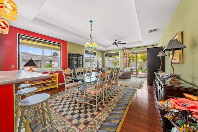 dining space featuring dark hardwood / wood-style flooring, a chandelier, and a tray ceiling