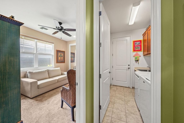 interior space with ceiling fan, light tile patterned flooring, washing machine and dryer, cabinets, and sink