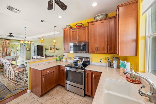 kitchen featuring decorative light fixtures, stainless steel appliances, sink, kitchen peninsula, and light tile patterned floors