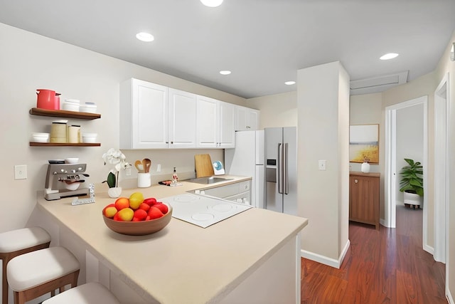 kitchen with a peninsula, a breakfast bar area, light countertops, and white cabinets