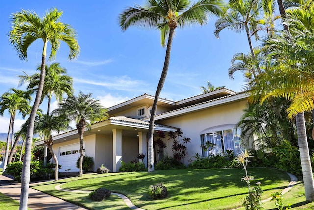 view of front facade with a front yard, an attached garage, and stucco siding