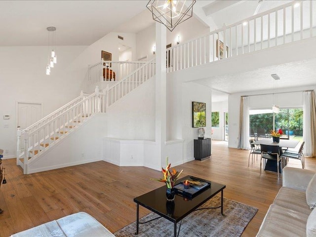 living room with wood-type flooring, a towering ceiling, and an inviting chandelier