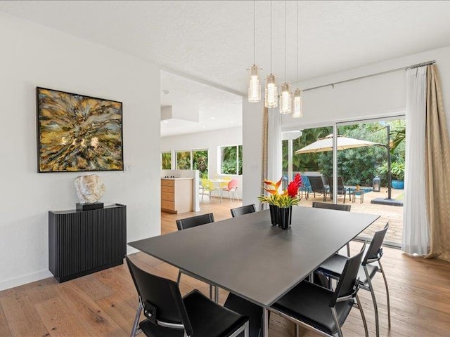 dining area with a notable chandelier, light hardwood / wood-style floors, and a textured ceiling