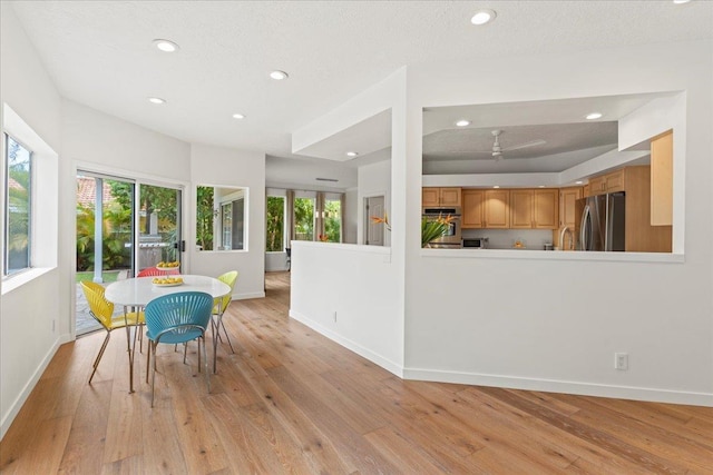 dining space featuring a textured ceiling, light hardwood / wood-style flooring, and lofted ceiling