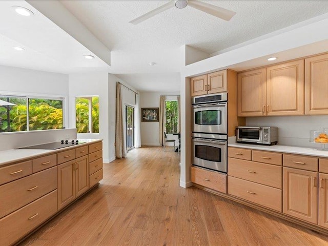 kitchen featuring light hardwood / wood-style flooring, light brown cabinetry, a textured ceiling, black electric cooktop, and stainless steel double oven