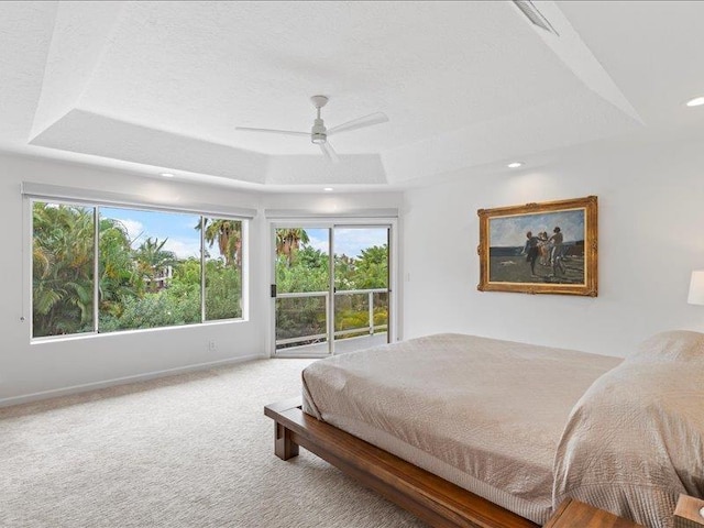 carpeted bedroom with ceiling fan and a tray ceiling